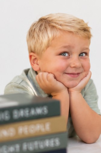 Boy resting his chin in his hands beside a stack of books