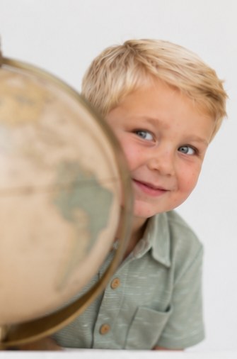 Boy peeking around a globe