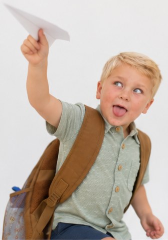 Boy sticking his tongue out while throwing a paper airplane