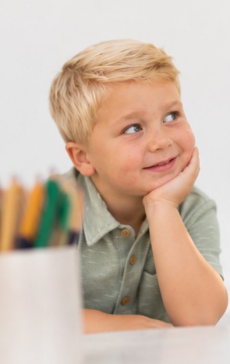 Boy giving a sideways glance with his chin in his hand